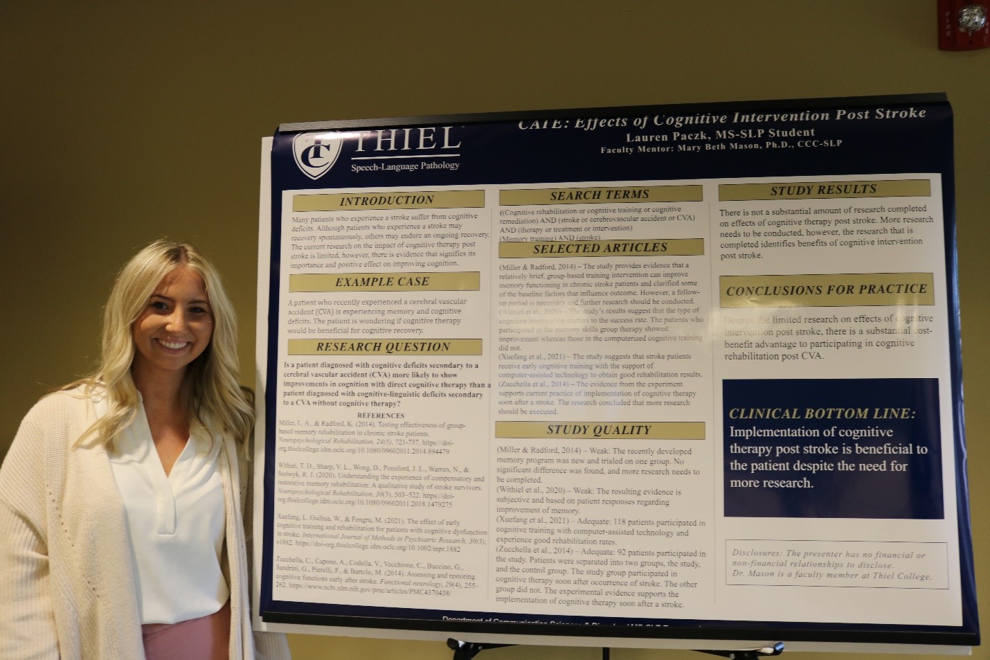 A graduate student from the Thiel Graduate Program in Speech-Language Pathology stands next to her research poster.