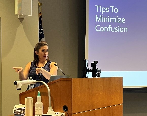 A professor from the Communication Sciences and Disorders program stands behind a lectern and gestures as she gives a presentation about the topic of memory.