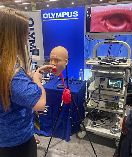Graduate student passing a flexible laryngoscope at a vendor’s booth.